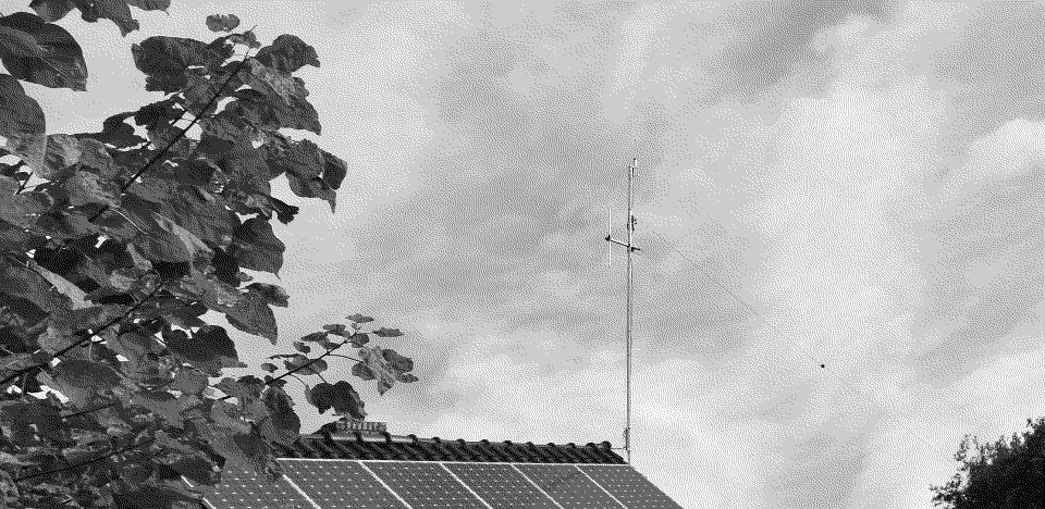 Impressie antenne PA4MRC zoals te zien van de straat. Een slanke mast net antennes en 2 spandraden van links naar rechts.